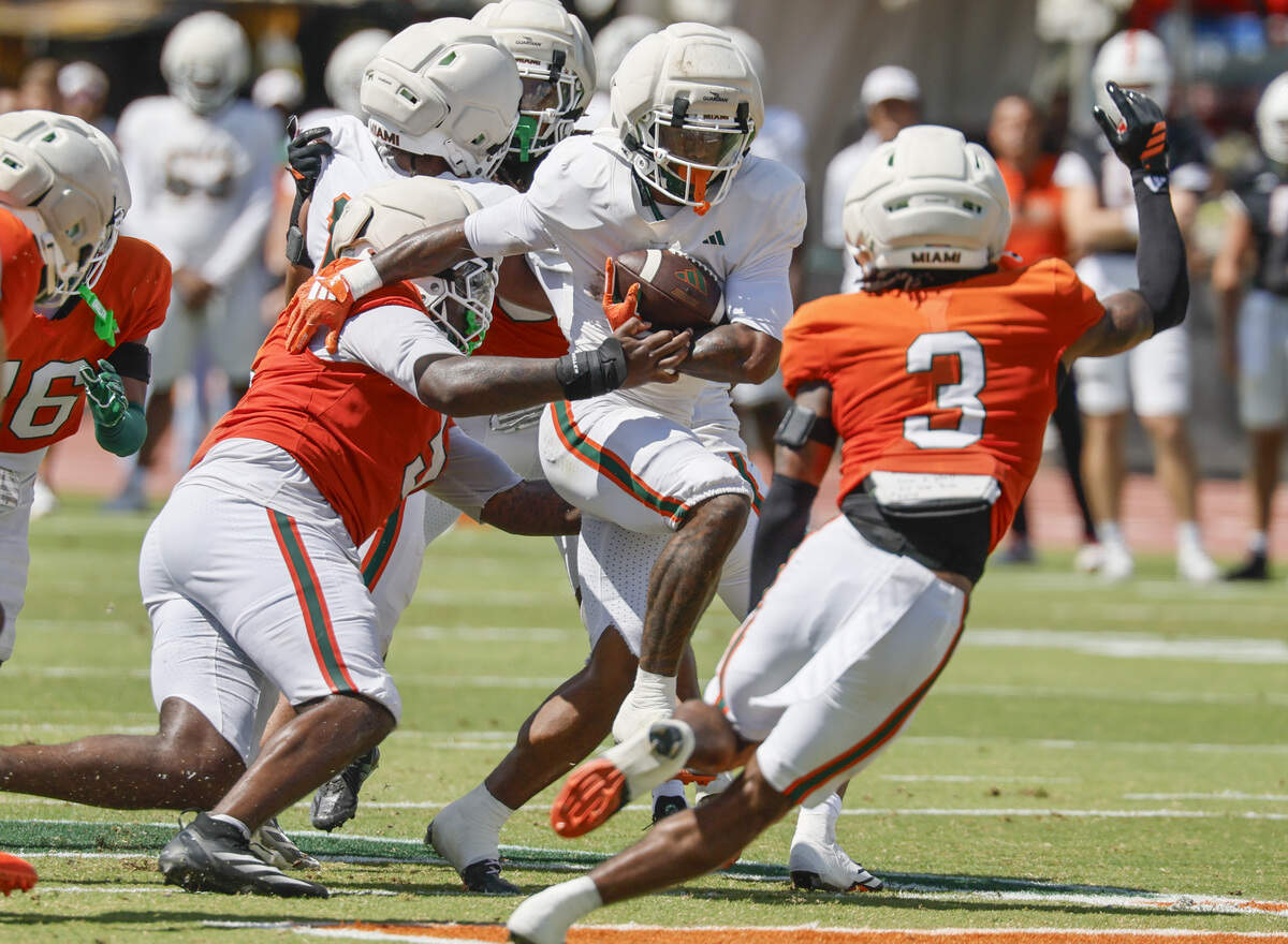 Miami Hurricanes running back Jordan Lyle (2) on a carry as Miami Hurricanes defensive lineman Justin Scott (5) and defensive lineman Bryce Fitzgerald (3) defend during UM’s spring football game at Cobb Stadium on the University of Miami campus in Coral Gables, Florida, on Saturday, April 18, 2026.